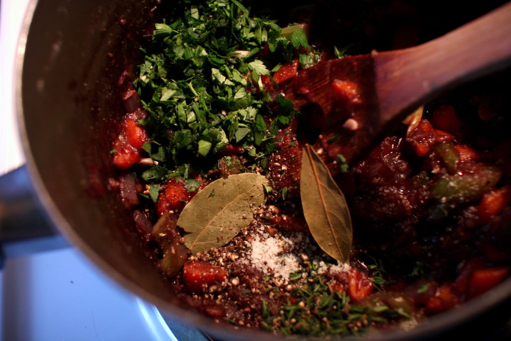 Photo of cottage pie filling and herbs and spices being added